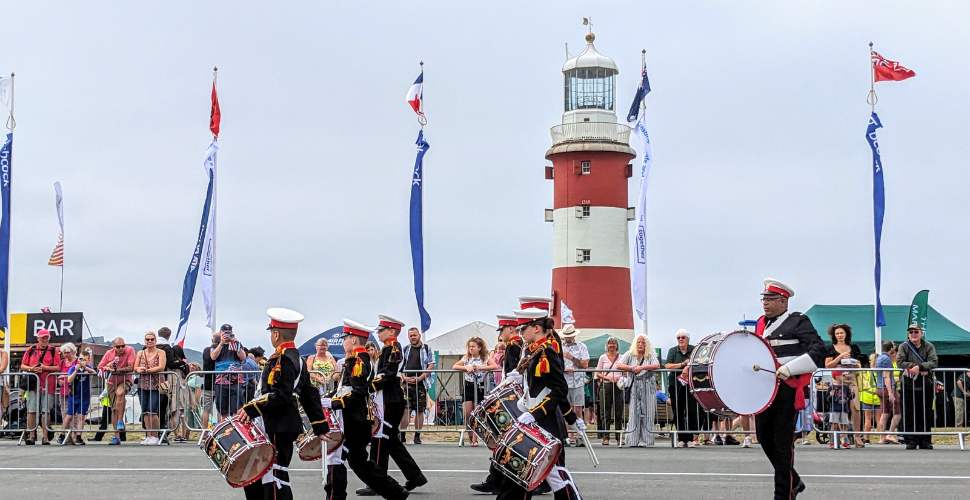 A Naval Band performs in front of crowds on the Hoe in Plymouth with Smeaton's Tower in the background